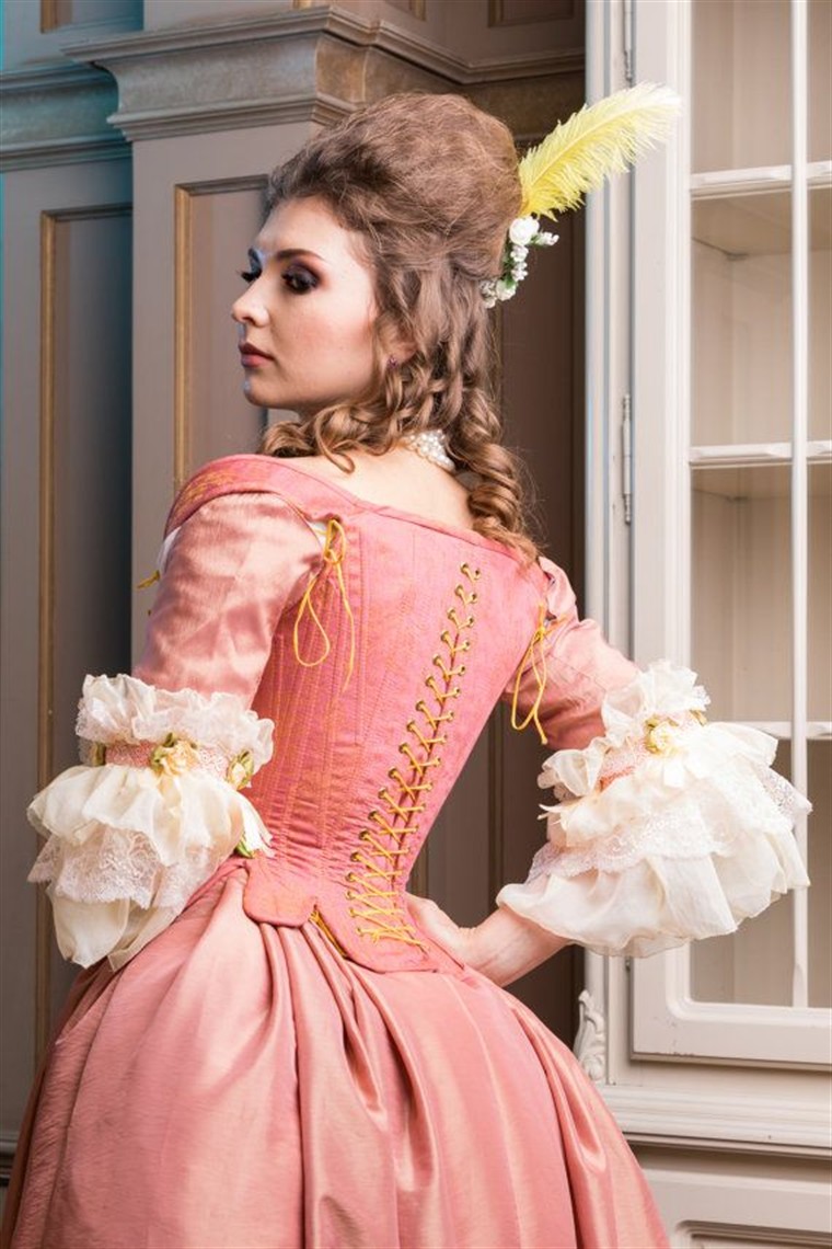 Rose gold baroque court gown on a dress form with ornate trim.